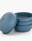 Set of four smoky blue rolled enamel bowls on a white background