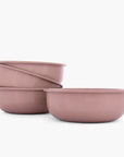 Set of four dusty rose rolled enamel bowls on a white background
