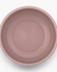 A dusty rose rolled enamel bowl on a white background