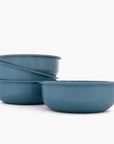Set of four smoky blue rolled enamel bowls on a white background