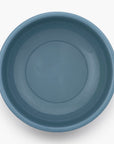 A smoky blue rolled enamel bowl on a white background