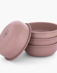 Set of four dusty rose rolled enamel bowls on a white background