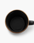 One black 5 oz enamel espresso cup with copper plated rim on viewed from above on a white background.