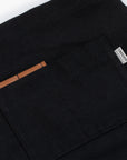 Close-up of a chest pocket on an a black apron with brown leather pad.