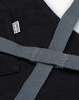 Close-up of a black apron with gray straps and visible Barebones brand label.