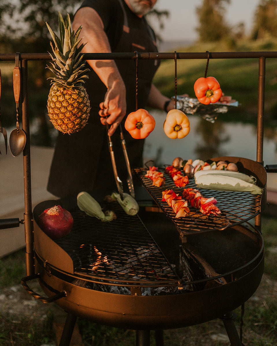 Person grilling vegetables on a Cowboy Grill outdoors